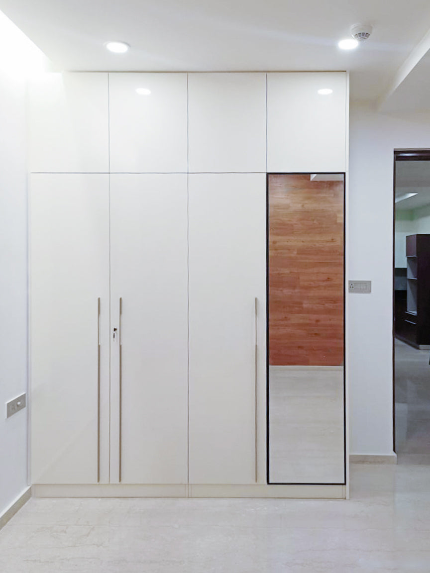 Modern white wardrobe with sleek handles and a built-in mirror. 
