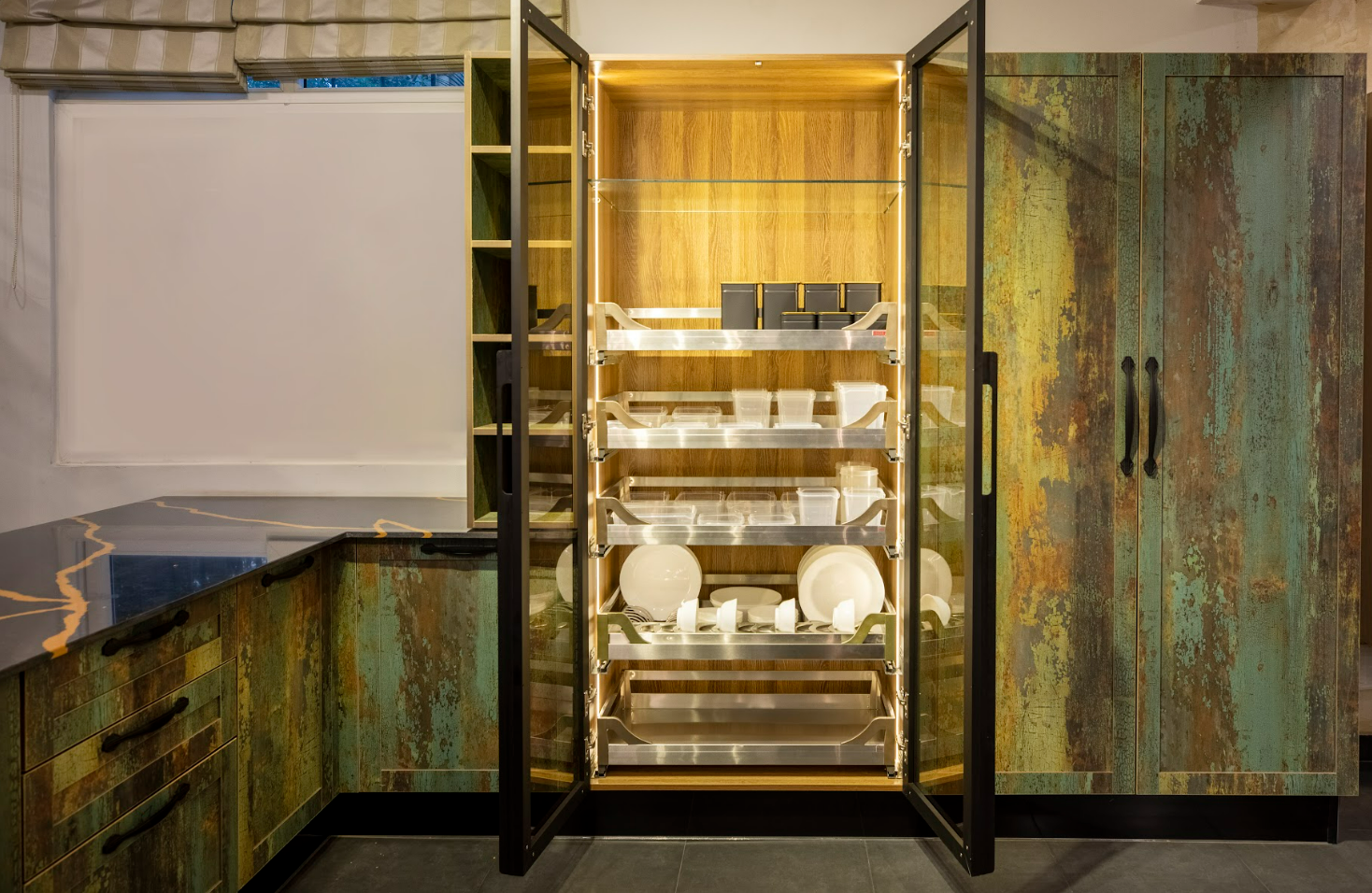 Rustic pantry with green and wood-toned cabinets and organized dishware.