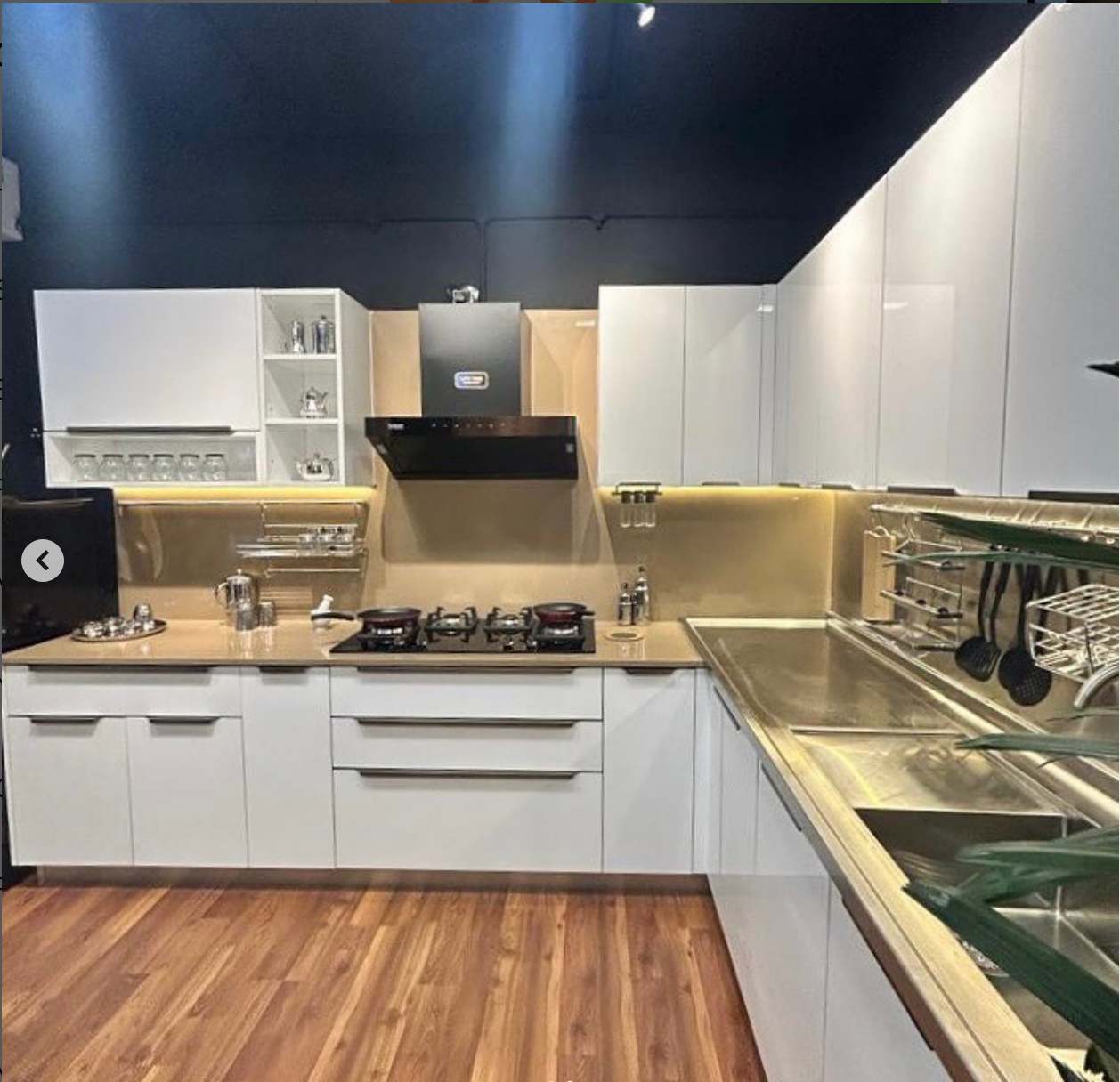 Modern white kitchen with sleek cabinets, a gas stove, and stainless steel sink. 