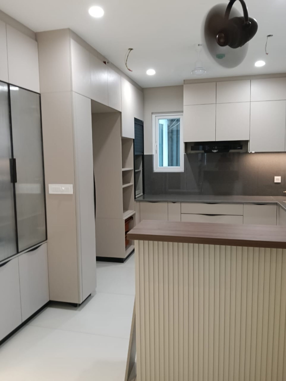 L-shaped kitchen · cream cabinetry with fluted-panel island and grey stone backsplash
