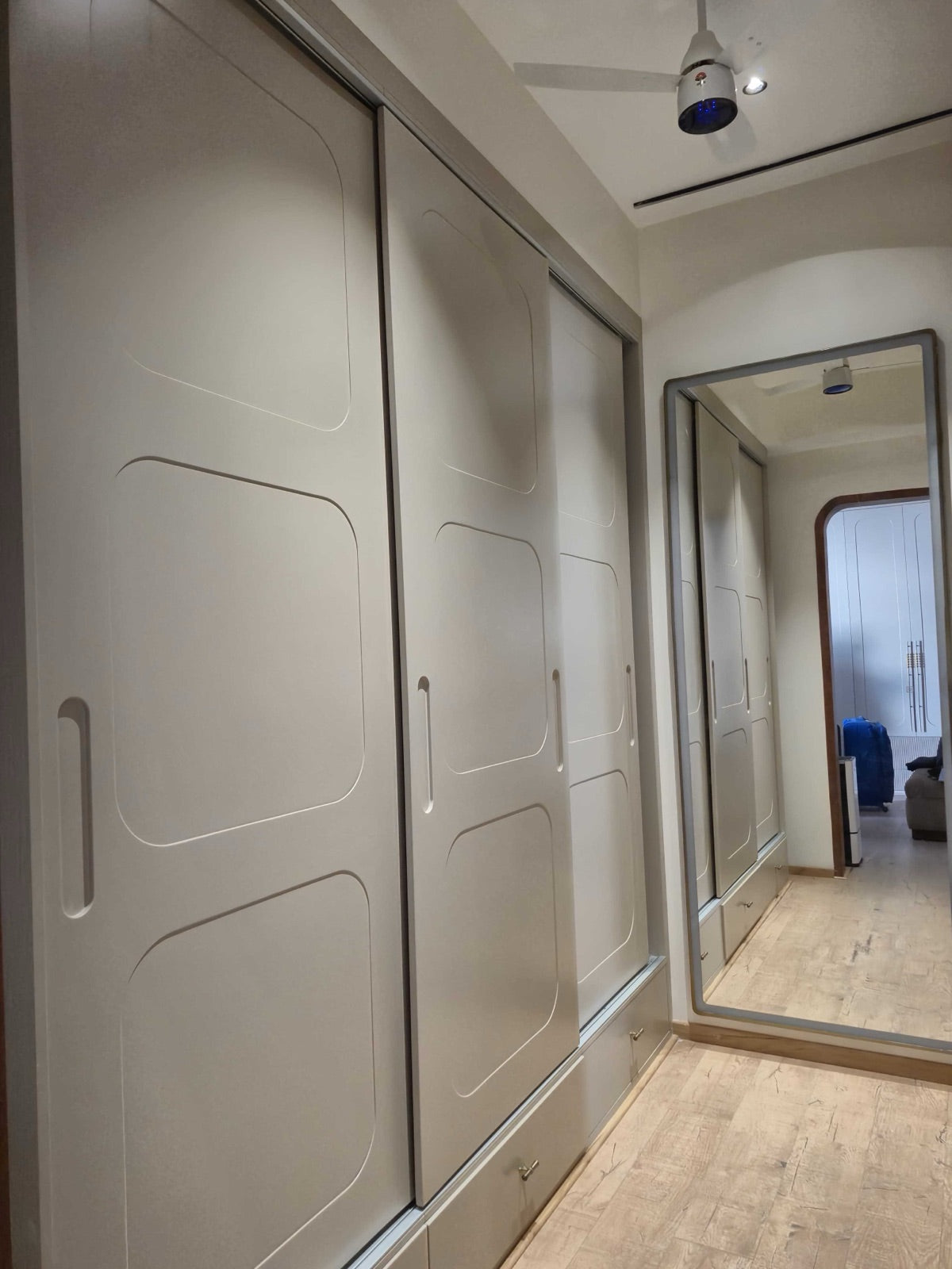 Wardrobe corridor · taupe sliding shutters beside full-length mirror