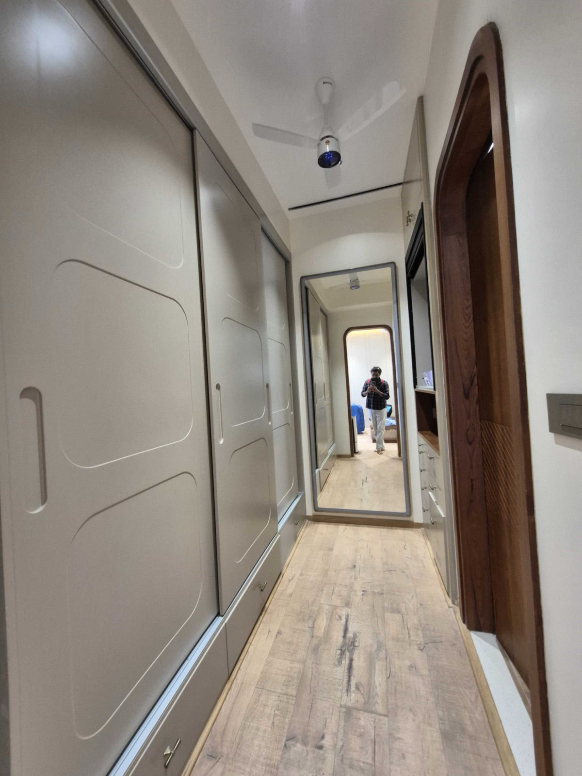Walk-through wardrobe passage · wood-look flooring leading to mirrored end wall