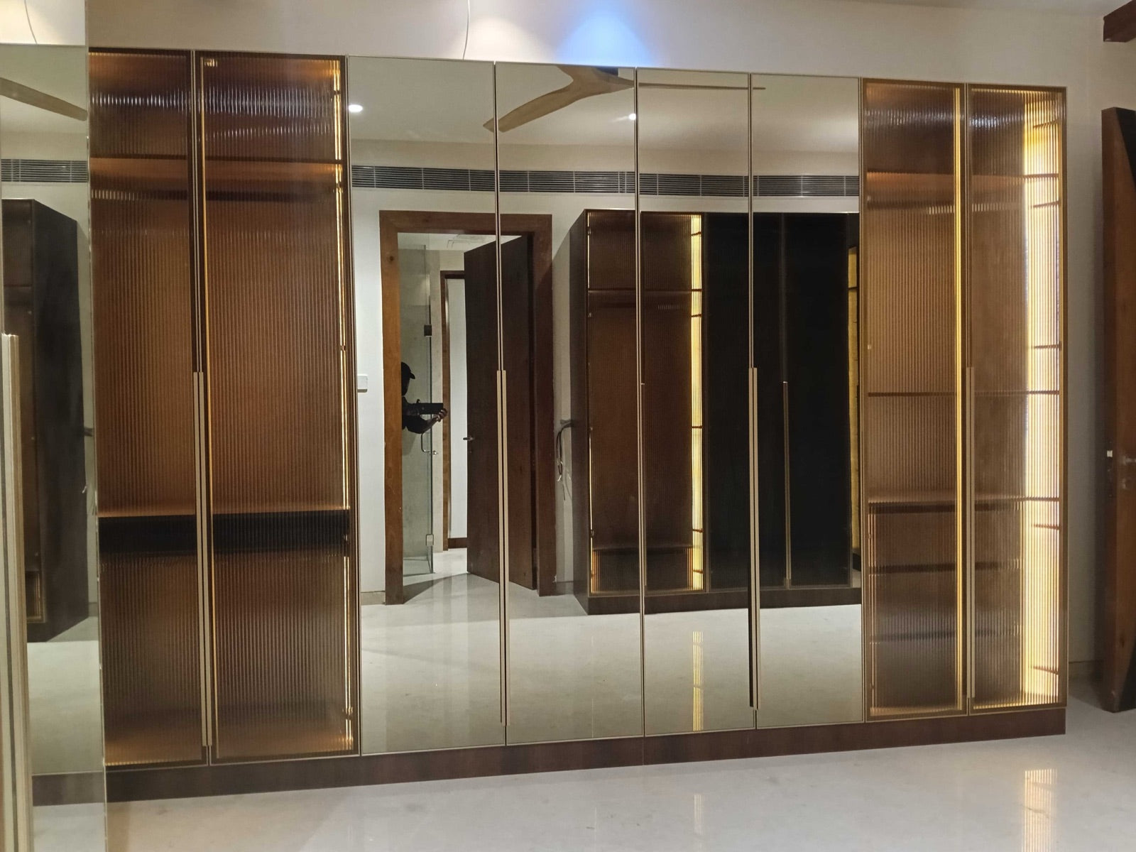 Wardrobe wall · mirror and reeded-glass sections with brass edge trim
