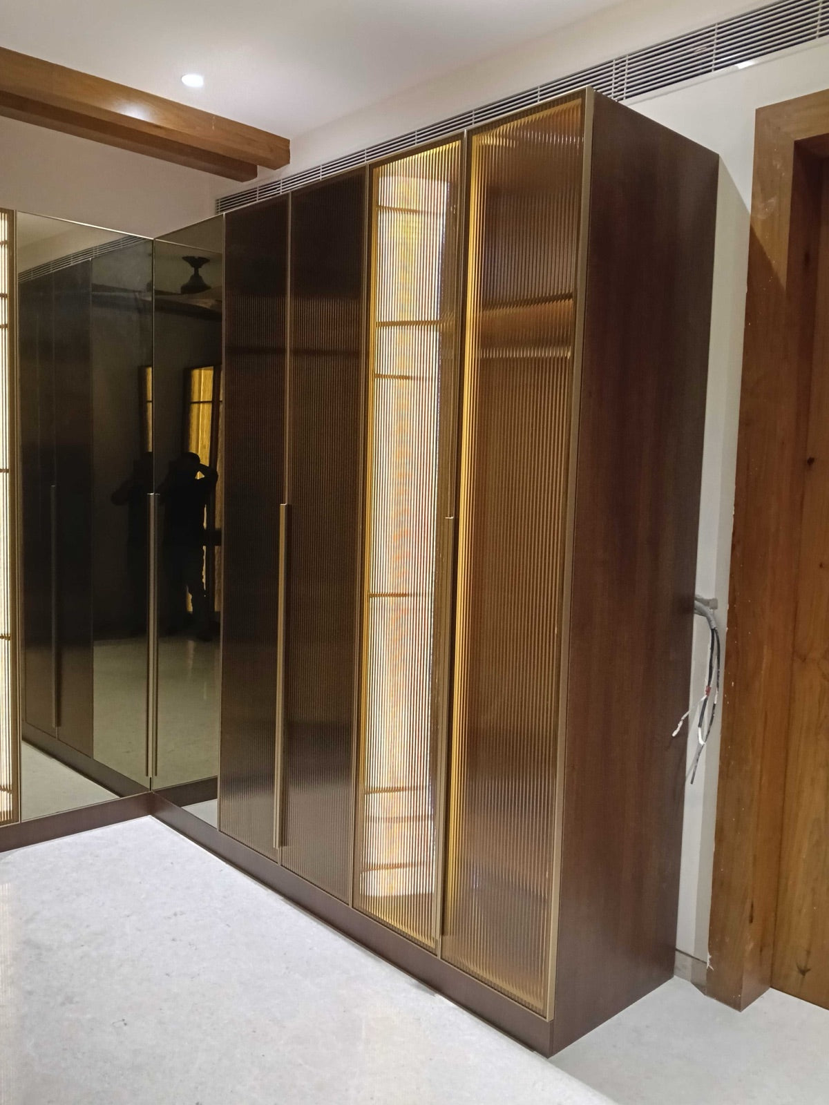 Reeded glass wardrobe door detail · warm LED backlighting