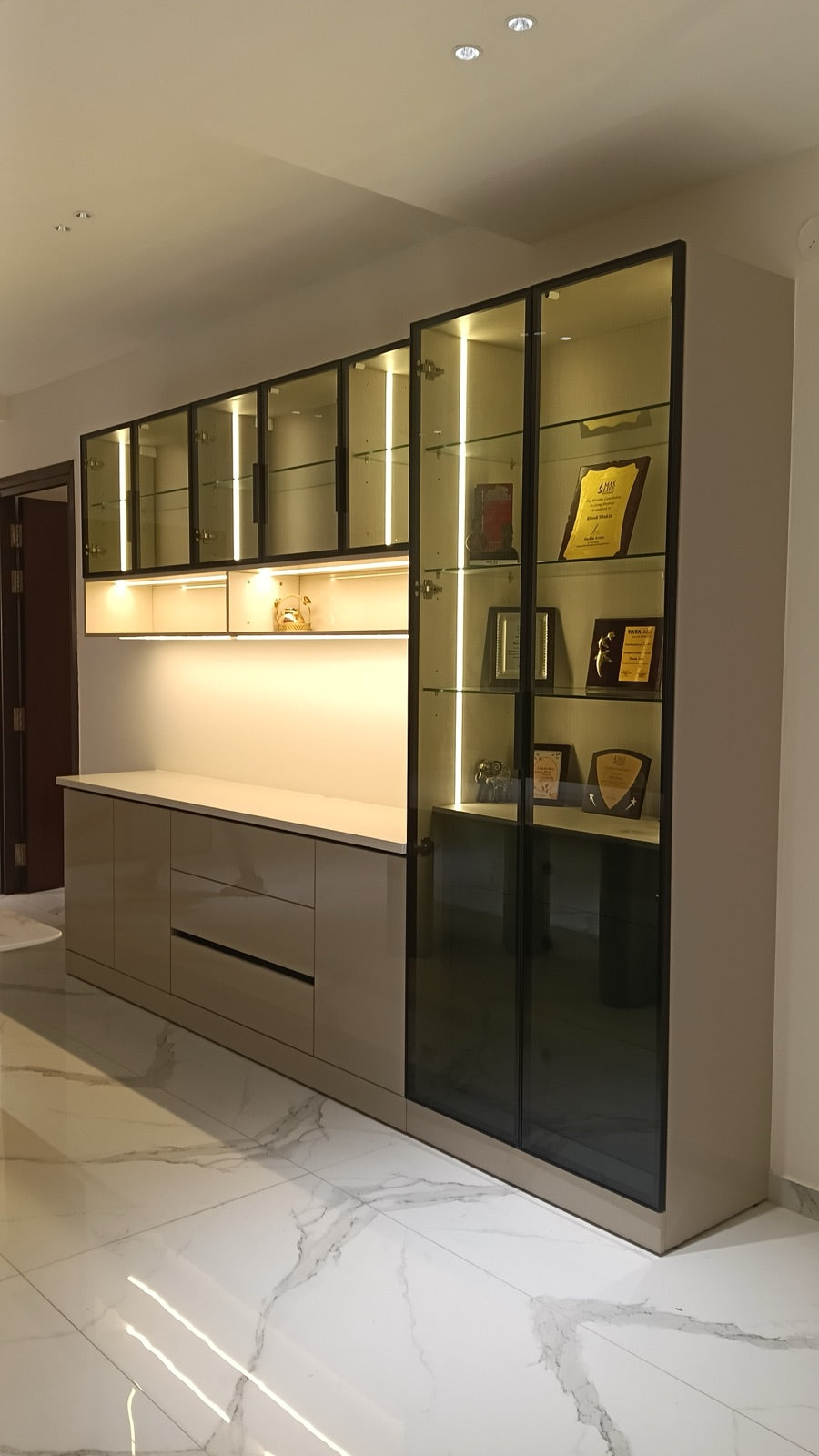 Display cabinet · glass doors with lit shelves showcasing framed awards