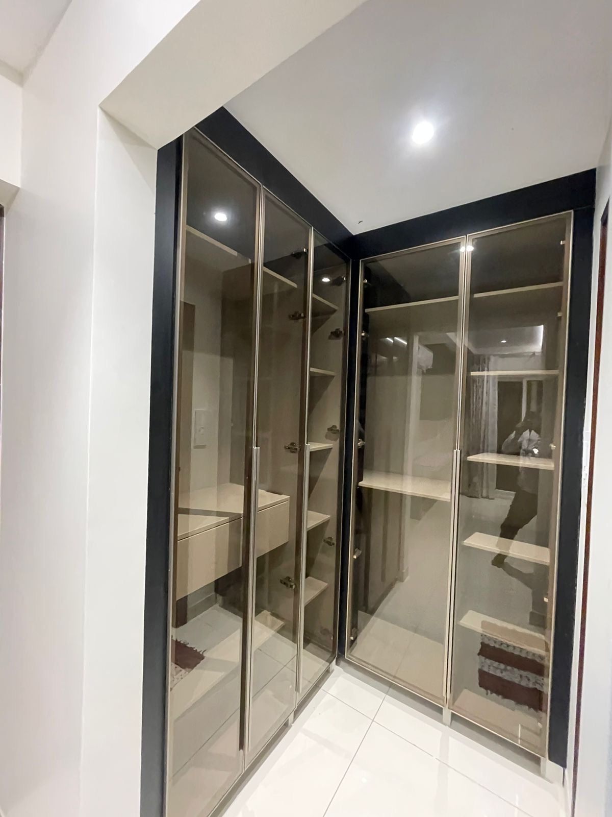 Walk-in closet with bronze-framed mirrored and smoked-glass wardrobe doors.