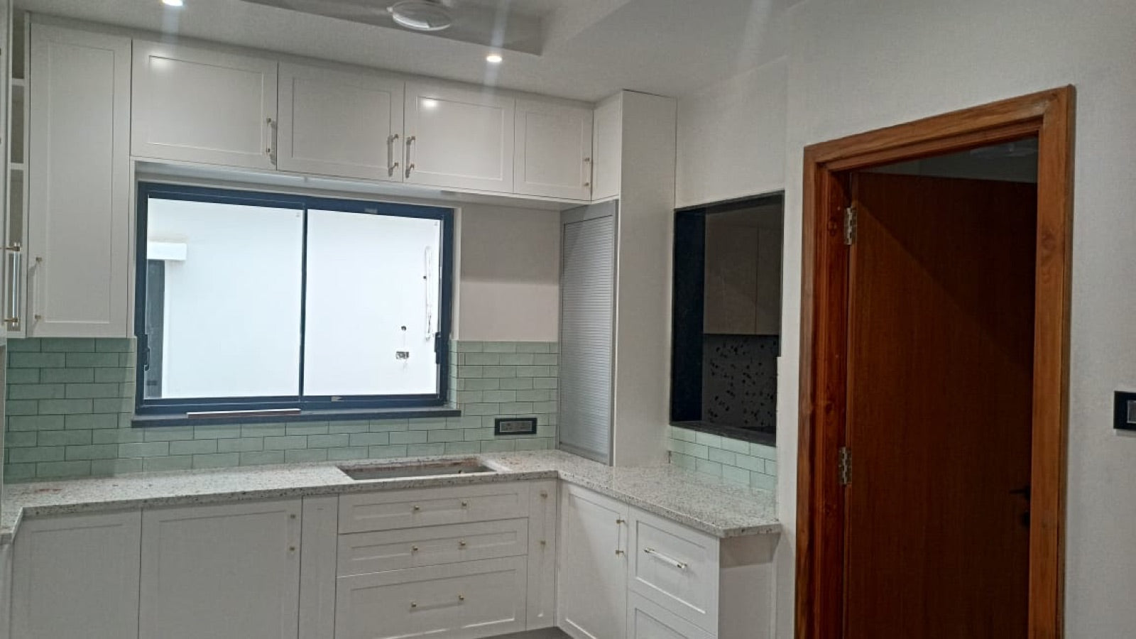 Kitchen with white shaker-style cabinetry and green subway-tile backsplash.