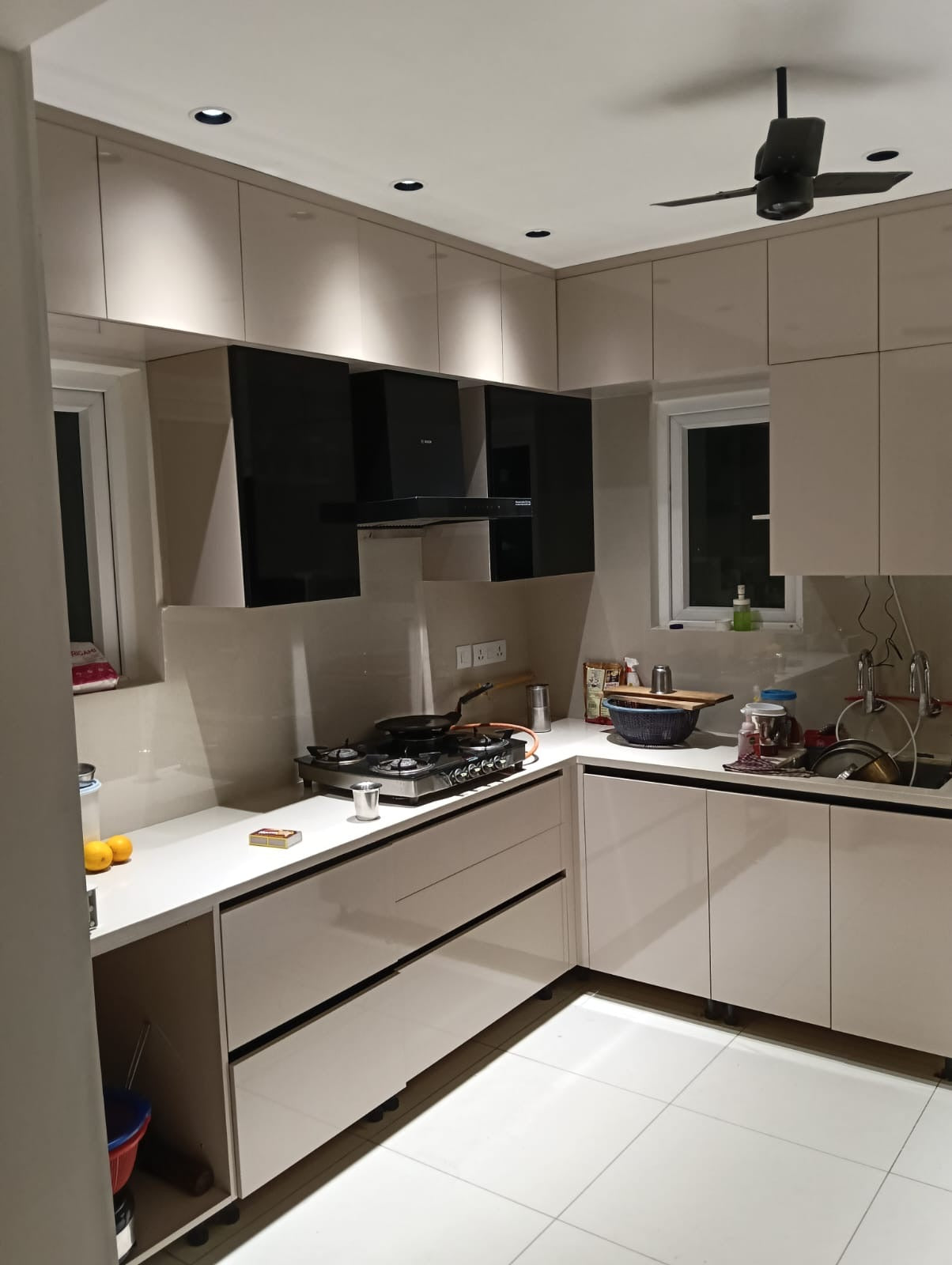 L-shaped kitchen in soft beige cabinetry with a black chimney hood.