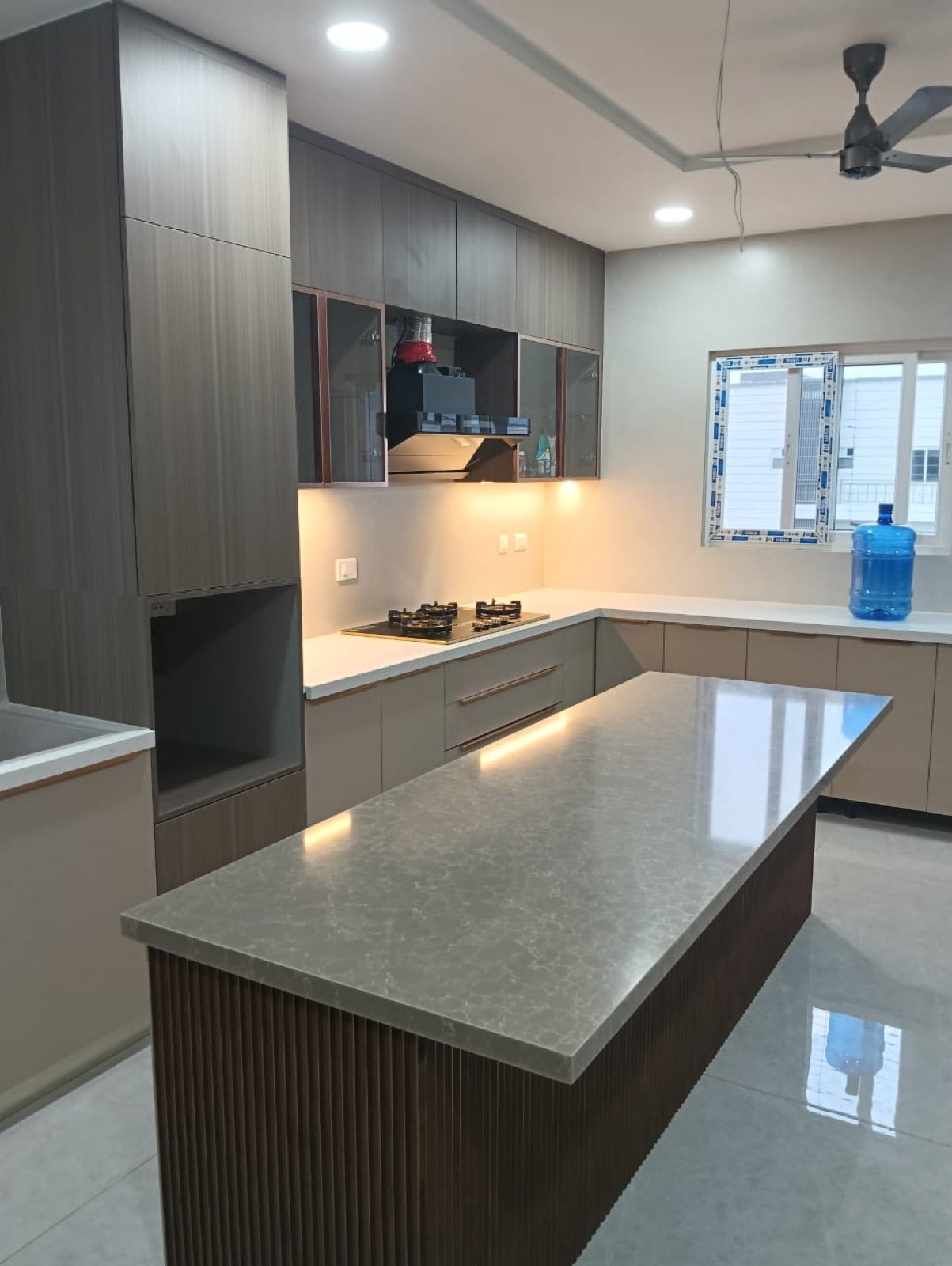 Kitchen island topped in grey stone-effect countertop over fluted panelling.