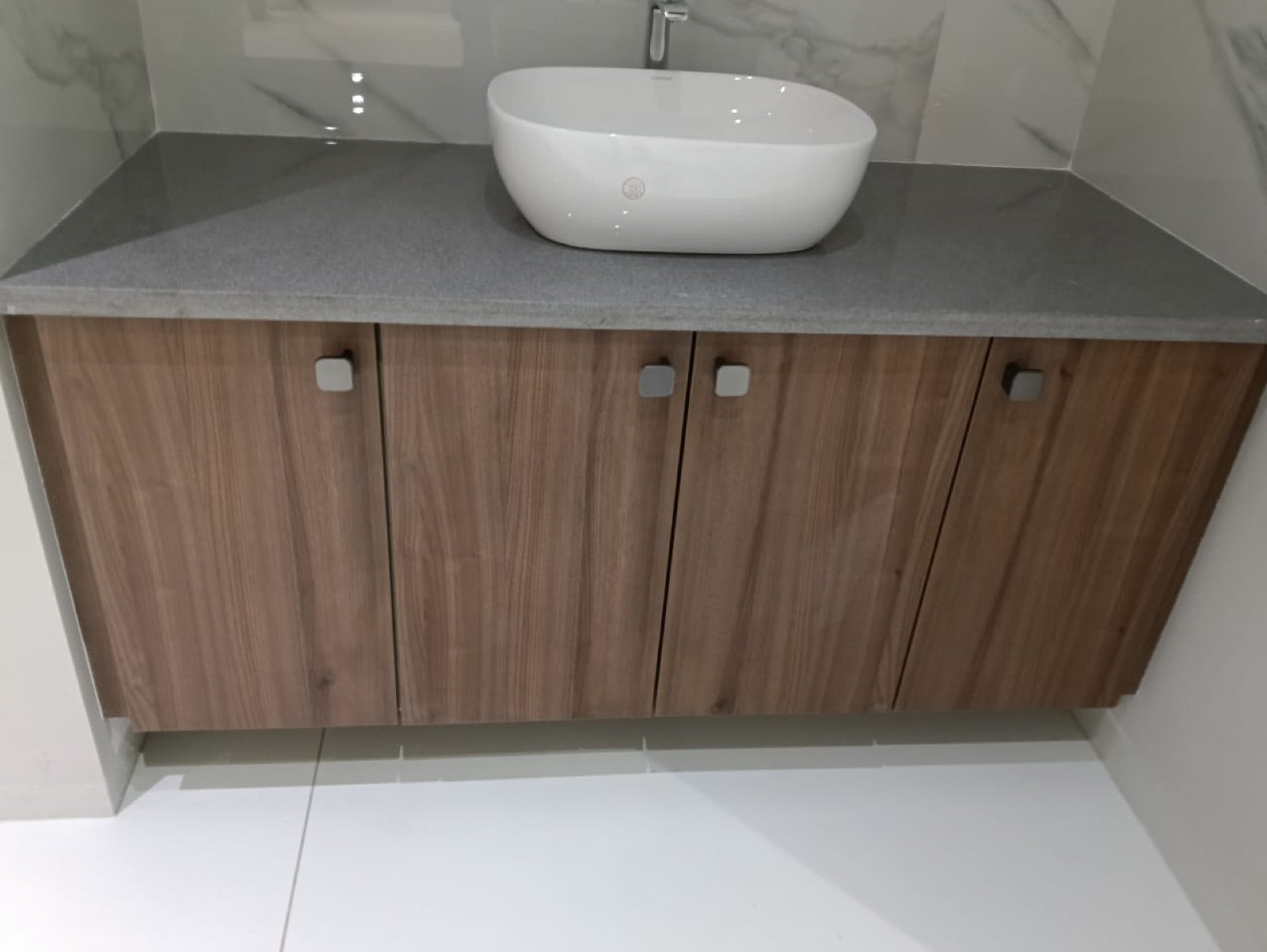 Bathroom vanity in warm wood-grain finish with a stone countertop.